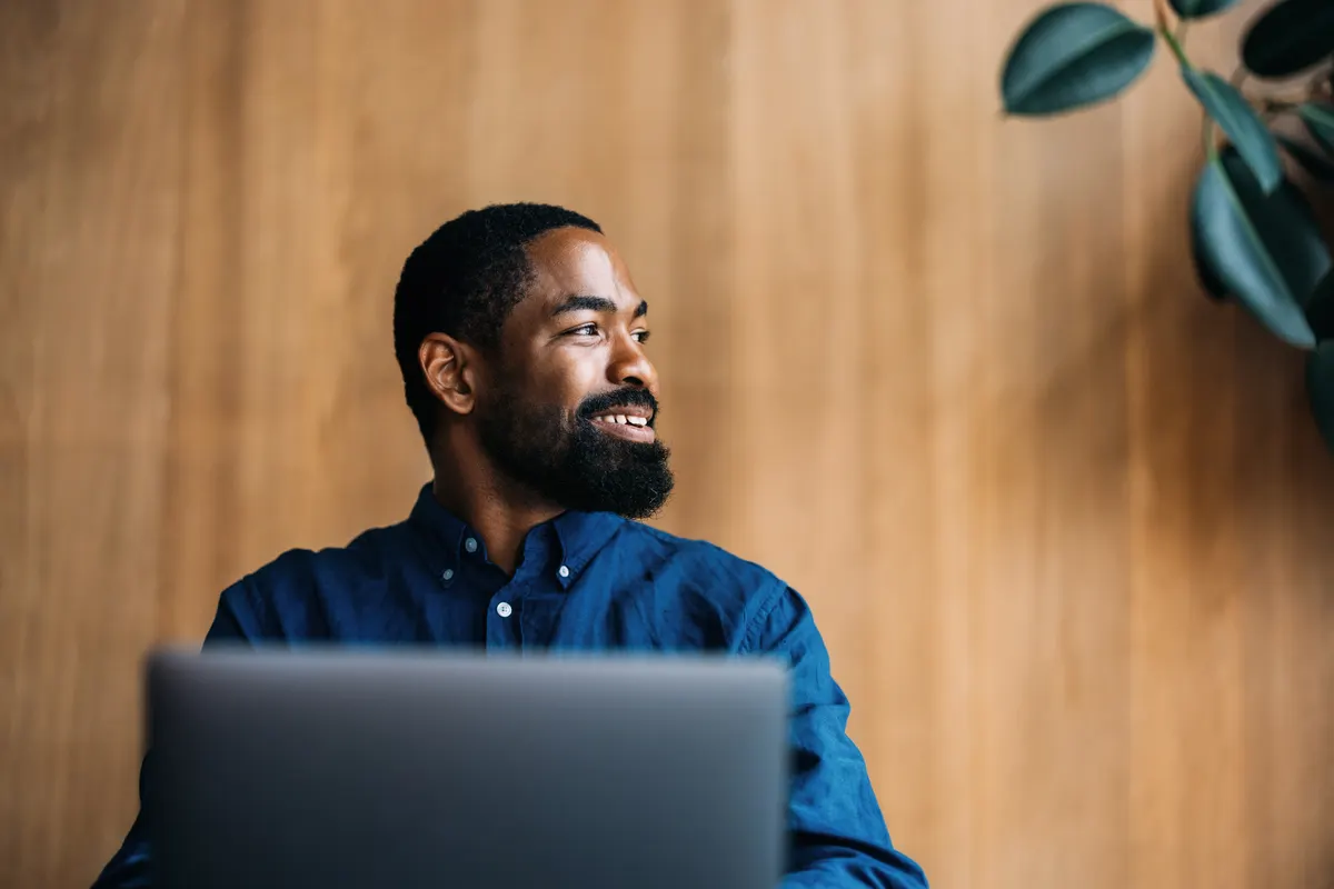 An IT administrator working at a laptop in a bright, plant-filled office