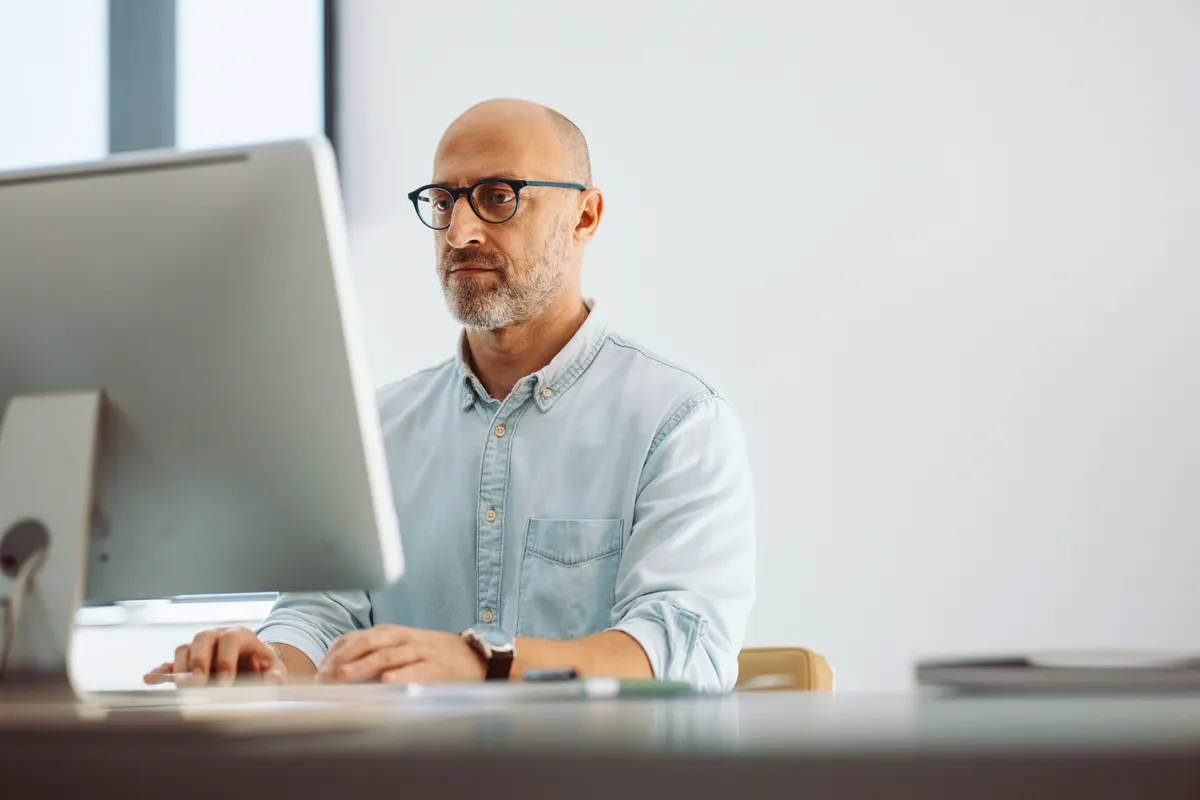 An IT manager focused on a desktop screen in a bright office