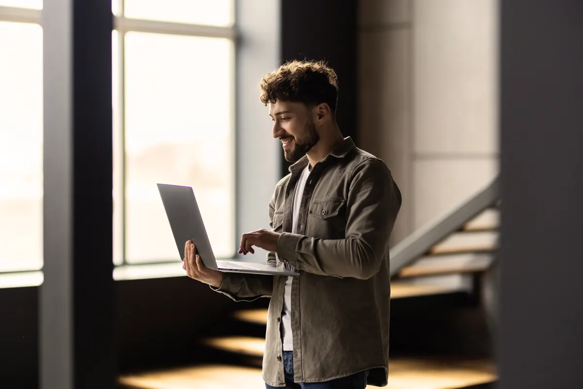 An IT support specialist smiling while working on a laptop