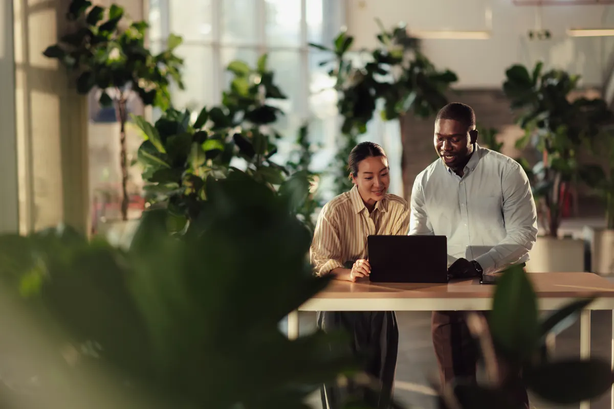 Two IT colleagues reviewing endpoint management together on a laptop in a bright office